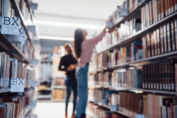 Blurred photo. Multiracial students in the library searching for the information together.